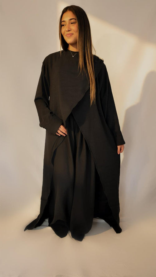 Ensemble drapé noir AZEL Paris porté de trois-quarts, broche dorée à l'épaule
