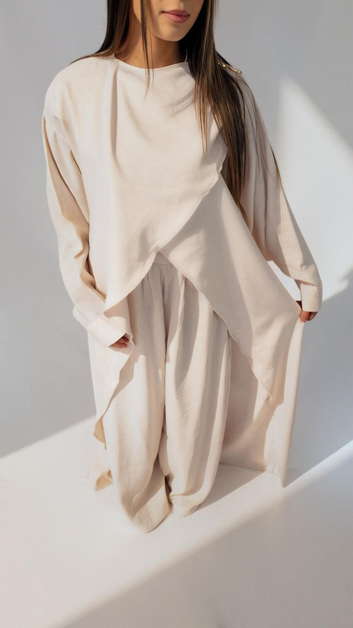 Ensemble drapé crème AZEL Paris porté de trois-quarts, broche dorée à l'épaule